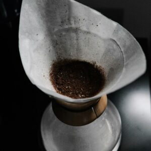 Filtro de papel con café molido sobre una jarra de preparación, visto de cerca